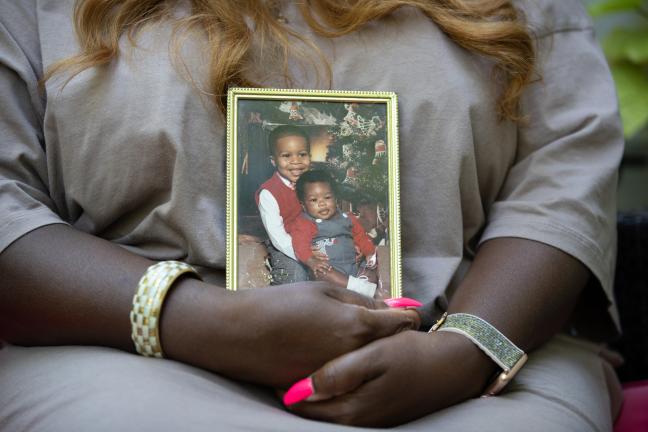 Saunders holds photo of two young sons. Today, they have flourishing careers and families of their own. 