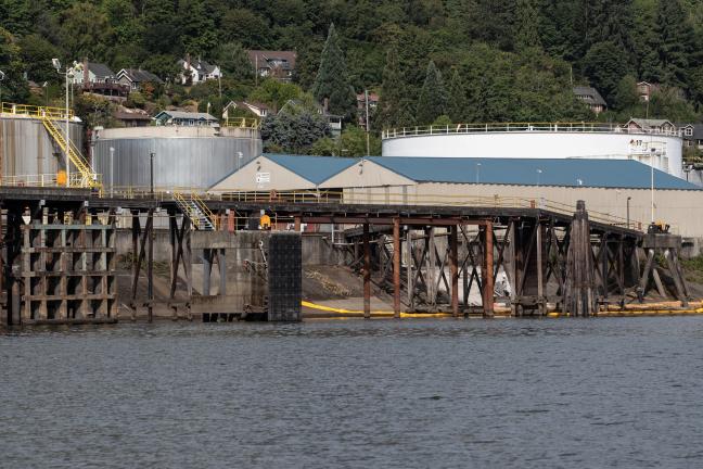 A series of fuel tanks along the Willamette River with Portland's West Hills in the background.