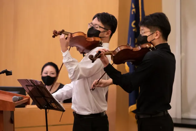 El comisionado Stegmann observa a los violinistas Paul y Tom Lee durante una proclamación en honor a los coreano-estadounidenses.