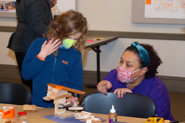 Chandra Robinson, arquitecta principal de LEVER, habla con un miembro de la comunidad sobre su diseño durante una reunión en la Biblioteca North Portland.