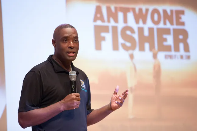 Antwone Fisher stands on stage to share his story with POIC + Rosemary Anderson High School and Multnomah County staff.