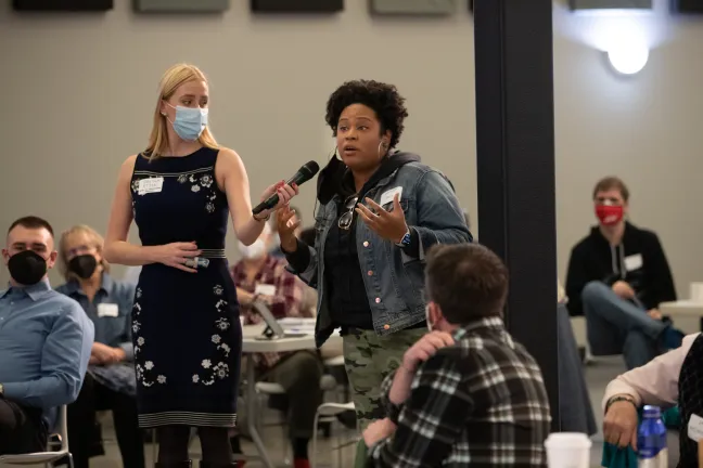 A woman holding the microphone while another woman speaks into it