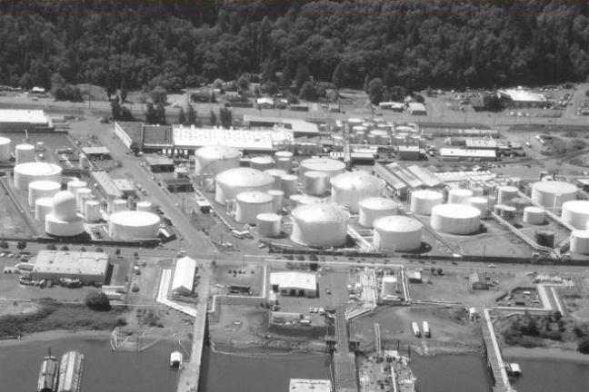 Large tanks for storing liquid fossil fuels adjacent to the Willamette River. 