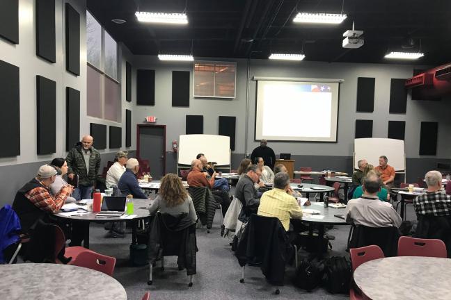 Picture of people sitting at round tables in a classroom