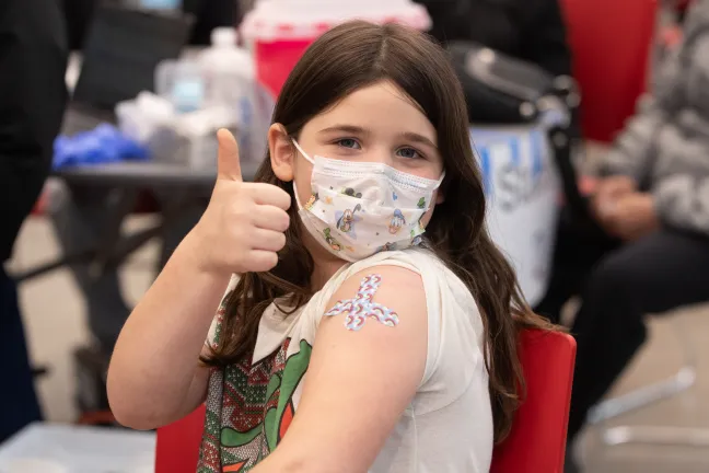 Lexi, 7 poses after getting her vaccination at the immunization clinic at McDaniel High School on April 13, 2022