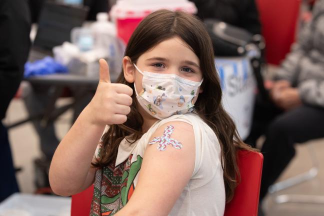Lexi, 7 poses after getting her vaccination at the immunization clinic at McDaniel High School on April 13, 2022