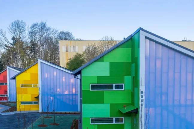 Image shows multicolored apartment buildings and a sidewalk: Argyle Gardens Apartments
