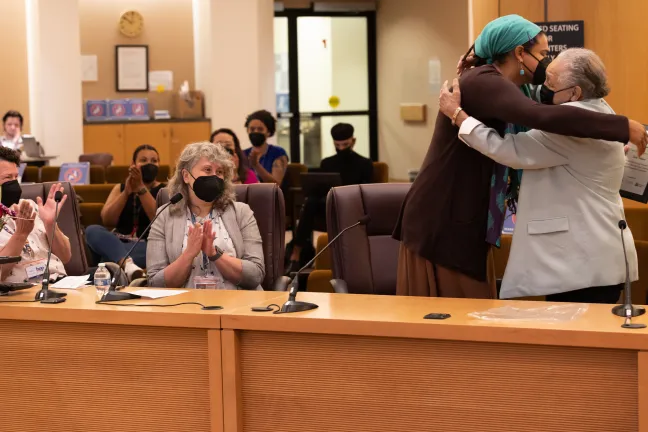 (Far right) Kathleen Saadat embraces Erin Waters (second to right) after presenting the award during the board meeting.