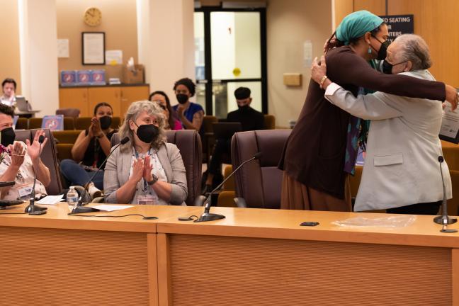(Far right) Kathleen Saadat embraces Erin Waters (second to right) after presenting the award during the board meeting.