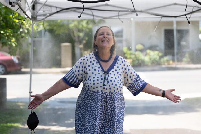 Beth Appert, a Public Health employee, cools off during her shift at a misting station.