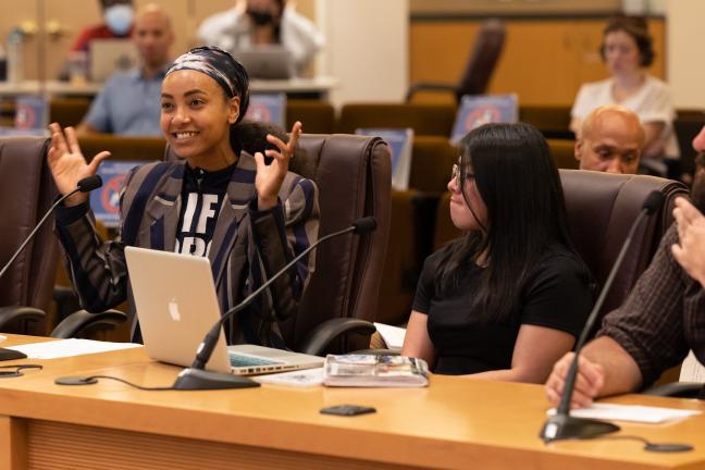 Esparanza Spalding, seated next to Cherie Hernandez-Archuleta and David Shine in the Multnomah County boardroom, motions with her arms while speaking to the board.