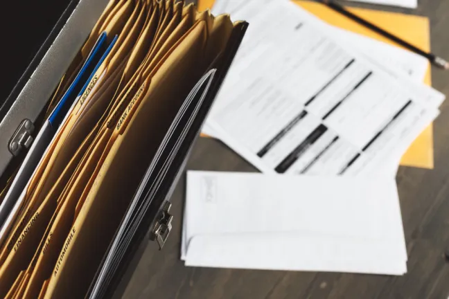 Looking down on an open file cabinet drawer. There are papers on the surface underneath the open drawer.