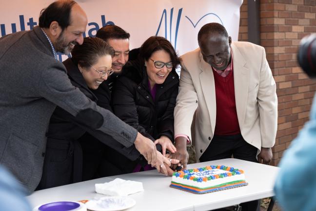 People cut a cake with words "Welcome Home" on it