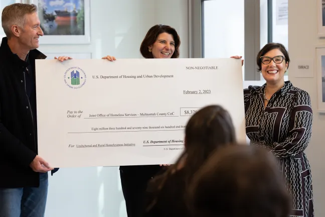 Portland Mayor Ted Wheeler, HUD Regional Administrator Margaret Salazar, and Chair Jessica Vega Pederson pose with a large ceremonial check