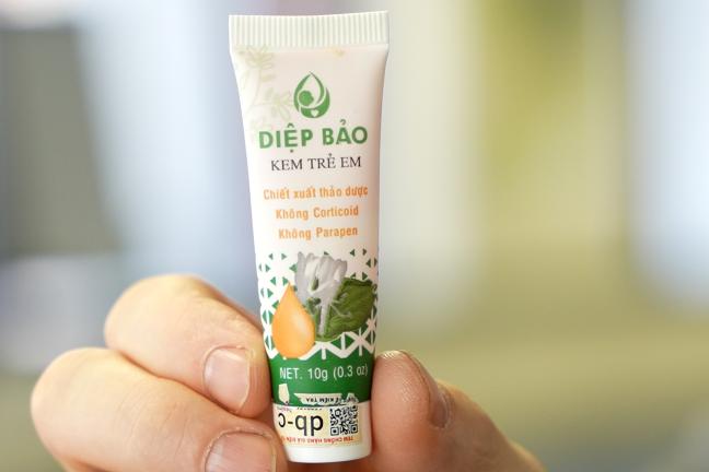 A photo of a white, green, and yellow tube of Diep Bao lotion with vietnamese lettering