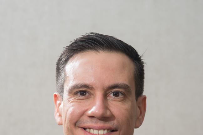 Photo of new Multnomah County Health Department interim director Valdez Bravo wearing a dark blue suit jacket, lighter blue shirt and dark blue tie