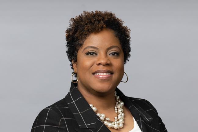 Photo of new Multnomah County Health Department interim deputy director of operations Chantell Reed wearing a black and white houndstooth suit blazer and red top