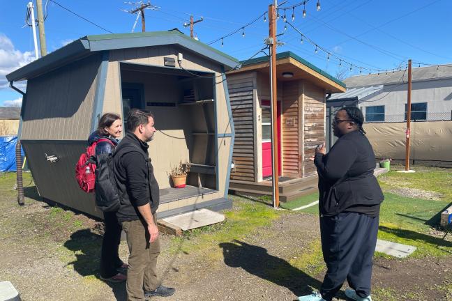 Three people stand outside a tiny home