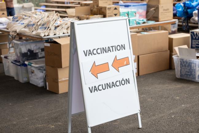 People line up to receive COVID-19 vaccines underneath a tent