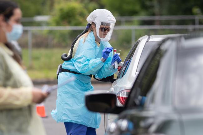 A County employee gives a COVID-19 test at a drive-thru clinic