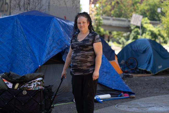 Photo of a woman standing with a wagon near a tent