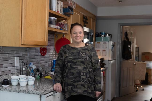 A woman stands in an apartment kitchen