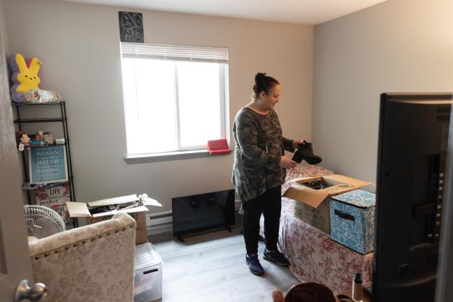 A woman unpacks a box in her bedroom