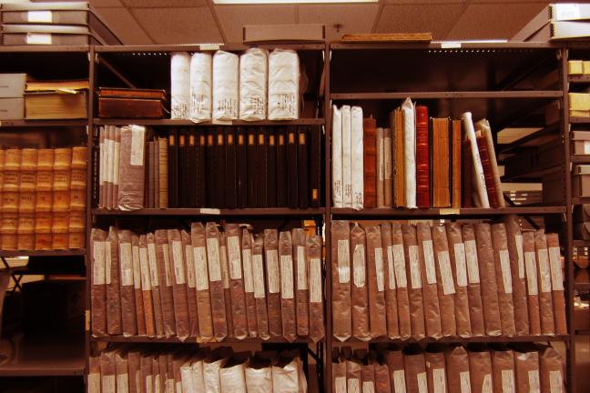 Several shelves in the Archives with rows of old volumes and ledgers