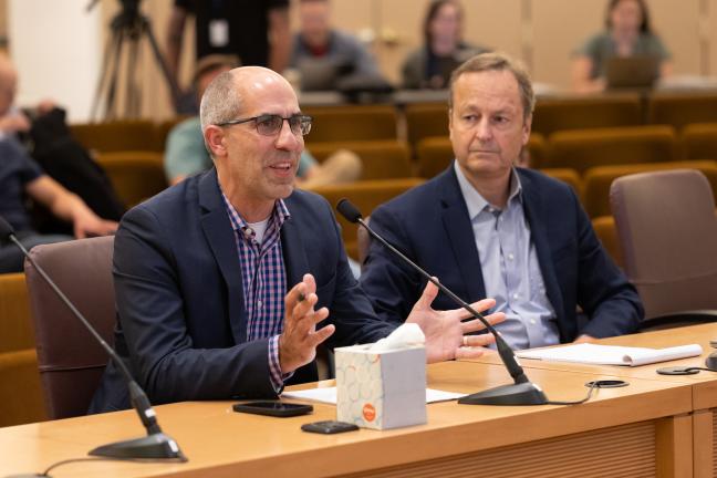 James Schroeder and Dan Field sit at dais in boardroom.