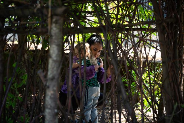 A preschool teacher hugs a child in the trees