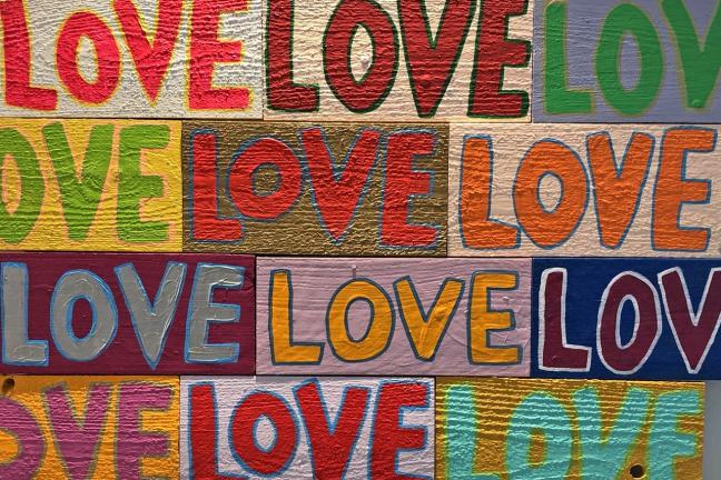 Bold and colorful painting shows the word "love" in a repeating pattern