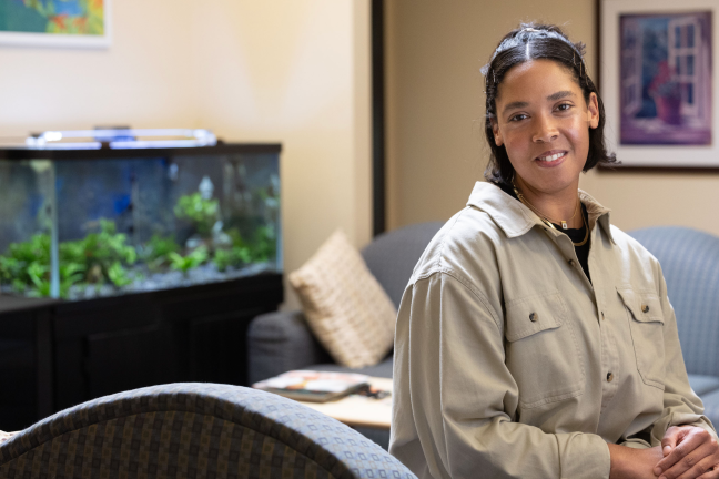 Photo of a woman inside a waiting room with a couch and fish tank.