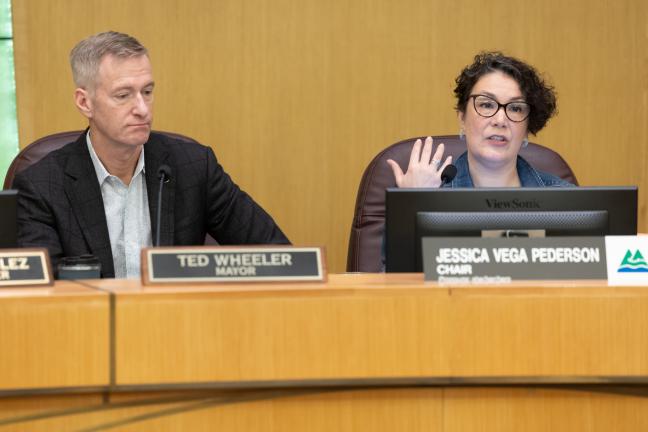 Mayor Ted Wheeler and Chair Jessica Vega Pederson sit at the dais