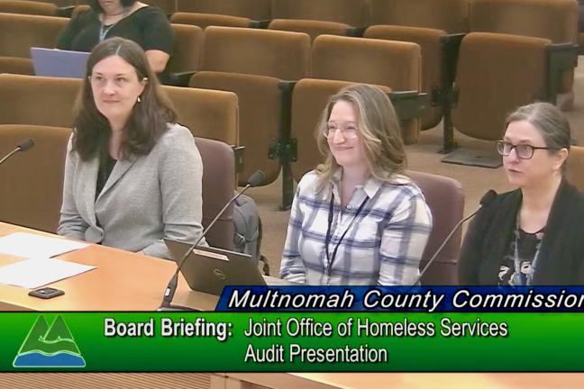 Nicole Dewees, Mandi Hood and Jennifer McGuirk sit at dais in board room. Text says "Multnomah County Commission Board Meeting: Joint Office of Homeless Services Audit Presentation"