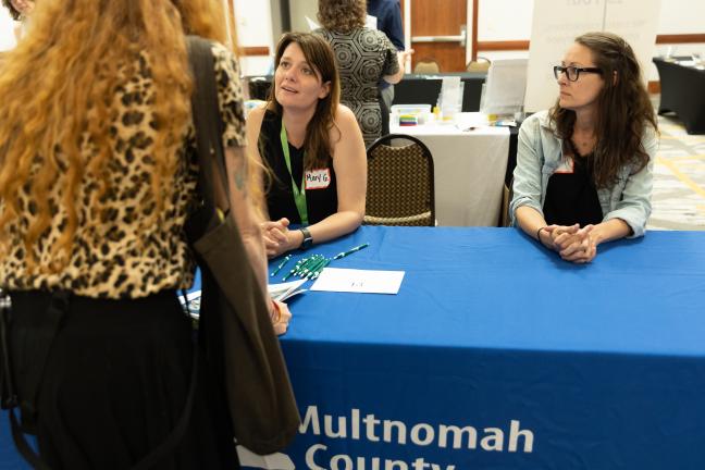 Two representatives from the Intellectual and Developmental Disabilities Services Division greet a visitor to the IDDSD Information Fair