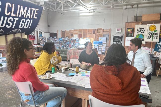 Members of the Climate Justice Plan Steering Committee talk while sitting around a table