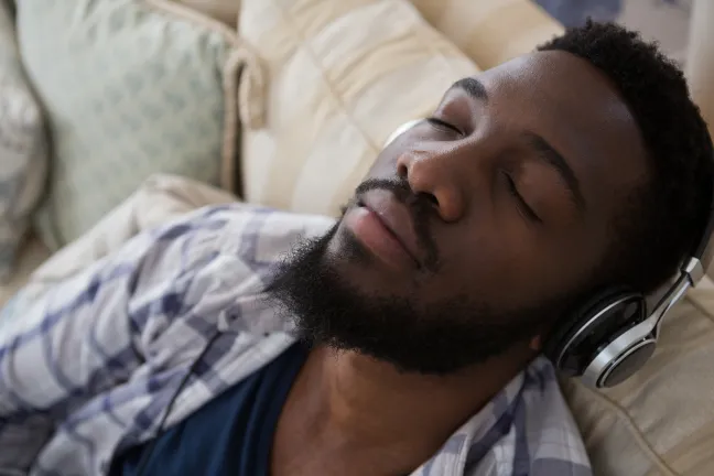 Person with eyes closed wearing headphones while sitting on a couch
