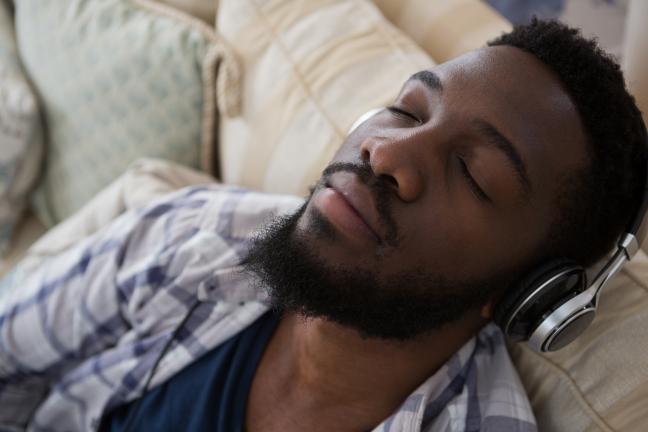 Person with eyes closed wearing headphones while sitting on a couch