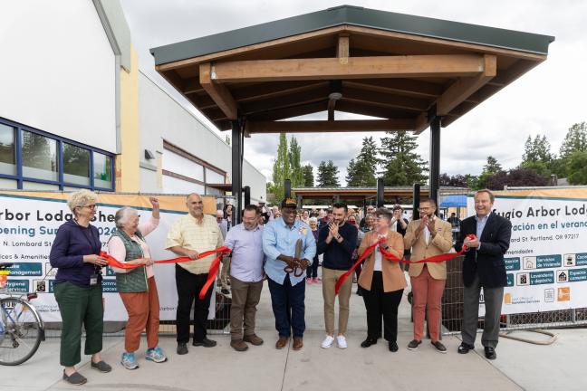 A group of people, including Commissioner Jesse Beason and Dan Field, hold up a red ribbon and giant pair of scissors.