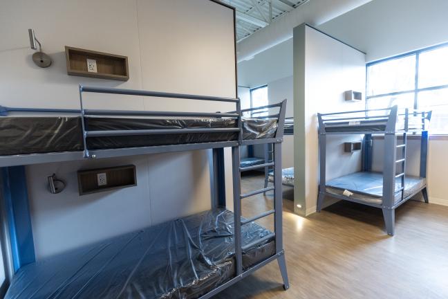 A room with bunk beds. Each bunk has a wall charger and a reading lamp.