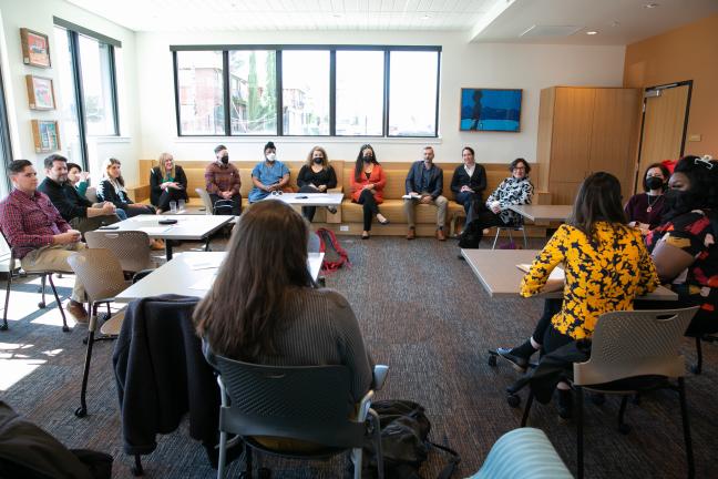 Group of people sit in a circle in a large room