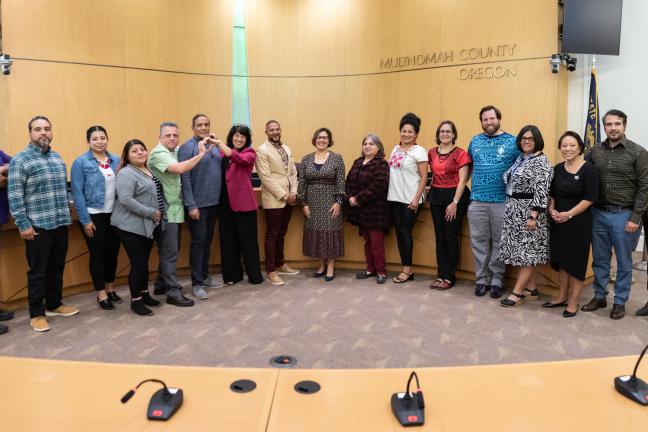 Board of commissioners and community members standing in the Board room for a picture.