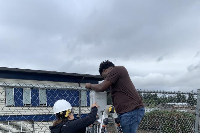 Wil Bridges, mechanical engineer, and his colleague Monica Wright mount a solar panel on a fence near Multnomah County’s Yeon Building.