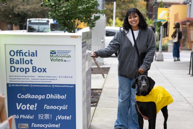 voter with dog on leash delivering ballot