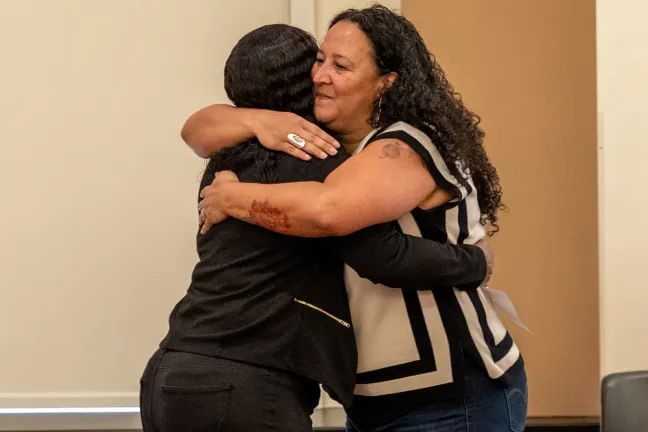 Commission Singleton embraces community member Perlia Bell at the swearing in.