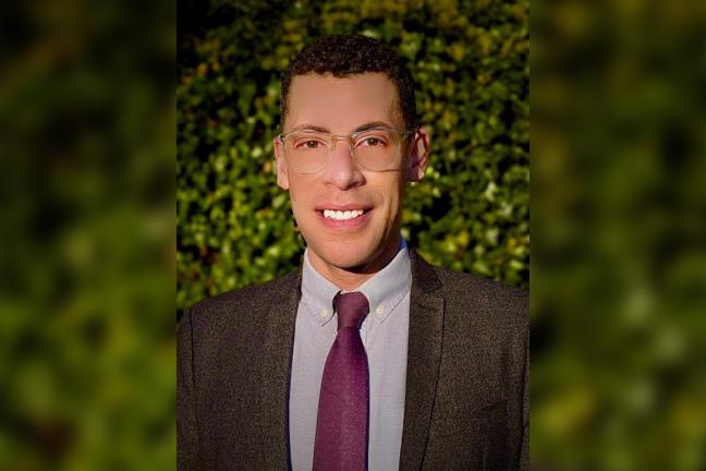 A photo of Brian Hockaday -- brown hair, glasses, brown suit jacket, lavender shirt and maroon tie.