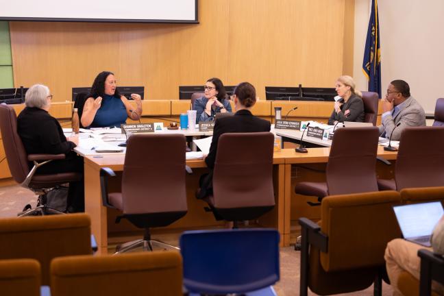 Commissioners sit around a table, speaking during a formal work session. 