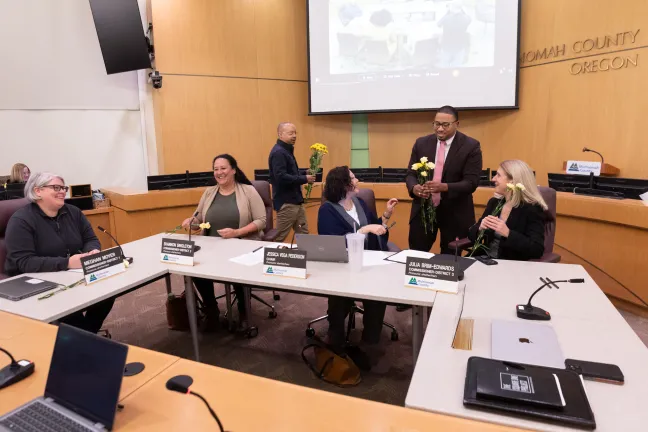 County Commissioner Vince Jones-Dixon (standing, right) and Stephan Herrera (standing, left) present flowers to women on the Board of Commissioners after reading of Women's History Month proclamation. Wednesday, March 19, 2025.