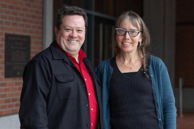 Shawn Postera and Brian Smith stand next to each other in front of the Multnomah Building