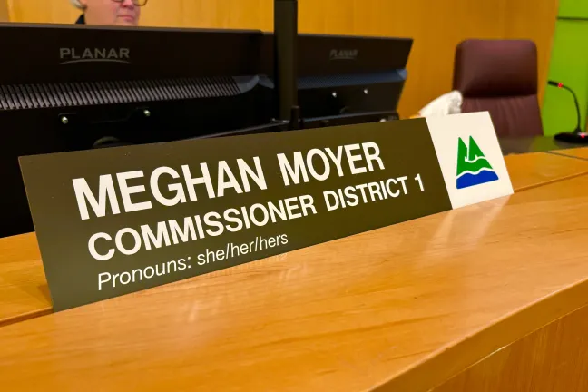 Dias name plate reading Meghan Moyer Commissioner District 1, Pronouns: she/her/hers